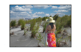 woman in sarong on sand dune looking at ocean