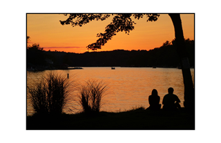 silhouette of couples by a sunset lake